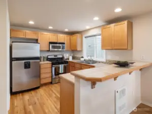 Spacious kitchen with a pantry closet, breakfast bar, and gas range. Photo shows Unit B (MLS 2276317) with reversed identical floor plan.