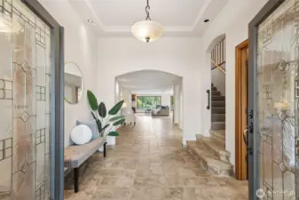Enter through the french doors, to the heated tiled floors through the foyer and straight to the amazing lake view!   (To the left is the guest room, to the right is the office, with closets, take the stairs up on the right, or continue to the main floor primary suite, and the easy flow gathering spaces)