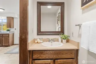 Conveniently located near the kitchen, this half bath includes solid wood cabinetry and durable hard surface countertops. A framed mirror and neutral finishes complete the space.