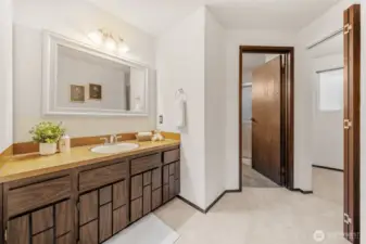 The Primary Suite bath includes a timeless vanity with generous counter space and under-sink storage. A private door leads to the separate 3/4 shower area for added convenience.