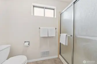 The Primary Suite shower features a timeless sliding glass enclosure and classic tile surround. A frosted privacy window allows natural light while maintaining discretion.