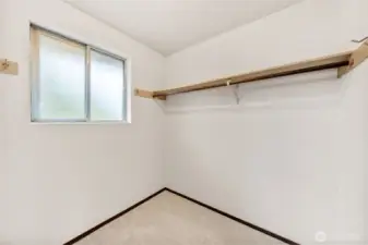 The primary suite closet offers generous hanging space and natural light from a frosted window. Neutral finishes and new carpet create a clean, functional storage area.