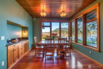Main house dining area showcases the views into Eastsound Village, Indian Island and Buck Mountain. Built-in custom cabinet for easy entertaining. This is just off the kitchen living area. Covered patio outside windows.