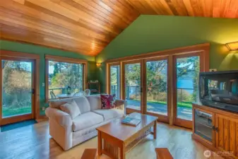 Guest house living space is finished with oak flooring, custom fir cabinets and vaulted ceiling. The space mirrors the main house with large windows, natural light and views across East Sound Bay,