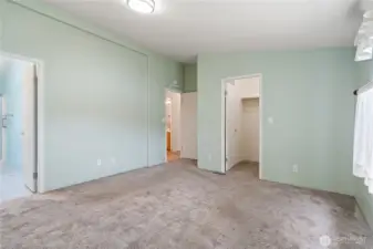 Primary bedroom showing access to bathroom, large closet, and hallway