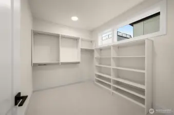 Primary suite walk-in closet with built-in shelving.