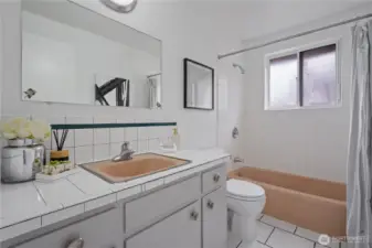 Full bathroom with tiled countertops and ceramic tiled flooring.