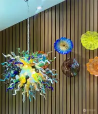 The Chihuly-style chandelier shines through the front window and greets your guests as they enter the home. An array of 10 back-lit art glass adorns the nearby wall.