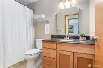 Full bathroom on the main level with tile floors and granite-topped vanity.