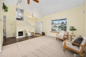 This view showcases the open layout of the living room along with the stairway leading to the upper level. A built-in shelf along the lower stair wall provides a practical spot to display, adding both character and function to the space.