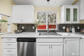 The sink area offers a deep stainless basin paired with an upgraded pull-down faucet. Surrounded by plentiful counter space and cabinetry, this workspace is both stylish and practical.