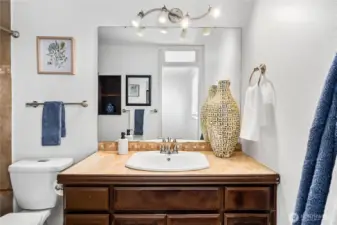 The primary bath features an extended vanity with plenty of storage, updated lighting, and a wide mirror that brightens the space. Neutral tones provide a versatile backdrop.