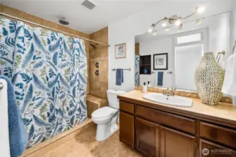 This full view of the primary bath highlights the combination of a large vanity, tiled shower, and practical layout. Warm finishes make it a comfortable and functional retreat.
