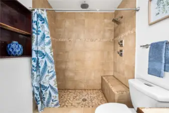 A spacious tiled shower with built-in bench seating offers both function and comfort. The tile surround with decorative accents adds a touch of style.