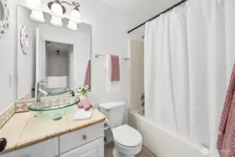 The full bathroom includes a tiled vanity with vessel sink, framed mirror, and updated lighting. A combination shower/tub with neutral finishes makes this space both stylish and functional for everyday use.