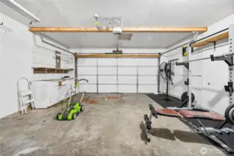 The attached two-car garage offers plenty of room for parking and storage, complete with built-in shelving and workspace. Versatile enough to accommodate vehicles, tools, or a home gym setup.