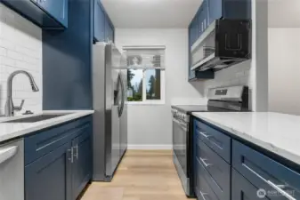 Updated modern kitchen featuring quartz countertops, custom cabinets, stainless steel appliances, and tiled backsplash.