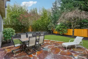 Custom stone slab patio overlooking lush, extravagant landscaping.