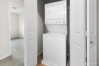 Bi-fold doors open to laundry closet with stacking washer and dryer set.