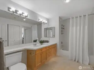 Bathroom with vanity, countertop space, and tub/shower combination. Clean layout with storage and mirror lighting. Connects to first bedroom.