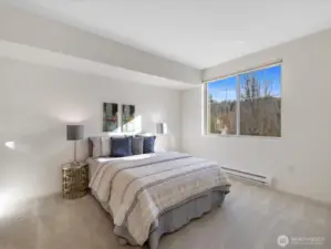 Bedroom with privacy, and large window providing natural light and views of surrounding greenery.