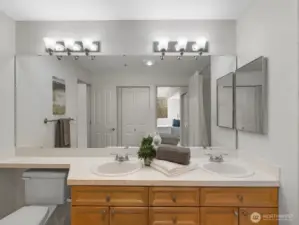 Ensuite bathroom with double vanity, dual sinks, and full-width mirror, providing functional layout with storage and lighting.