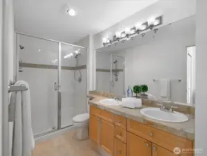 Bathroom with double vanity, dual sinks, and glass-enclosed shower. Primary bath connected to bedroom suite.