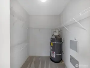 Walk in closet with built-in shelving with ample space, and easy access to the water supply.