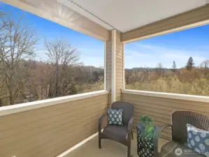 Covered corner deck overlooking wooded greenbelt with territorial views, providing outdoor space with year-round usability.