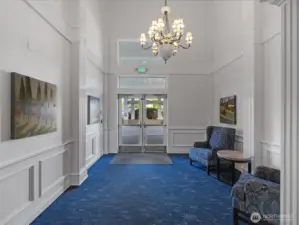 Secure building lobby with high ceilings, seating area, and controlled entry. Main entry point with direct access to interior corridors and elevator.