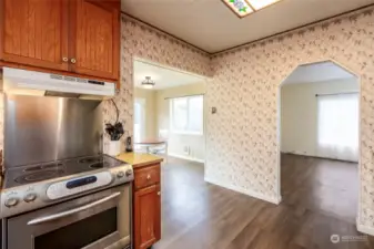 Stainless steel stove. Kitchen conveniently leads to living room through arched doorway and to breakfast/dining area.