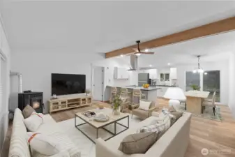 The staged living room demonstrates how spacious and comfortable this open-concept layout can be. The wood-burning stove anchors the room with a cozy touch, while the large seating area highlights options for arranging furniture. The space blends seamlessly into the kitchen and dining area, giving buyers a clear sense of how well the great-room layout lives.