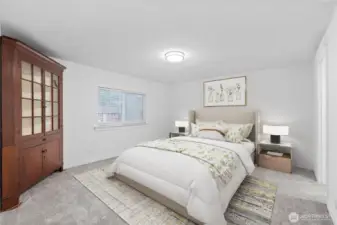 The staged primary bedroom highlights the room’s generous size and calming color palette. Soft carpeting, wide wall space for larger furniture pieces, and a centered window for natural light create an inviting retreat. The staging showcases how comfortably the room can accommodate a full bedroom set.