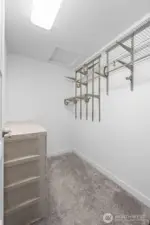 This walk-in master closet offers efficient storage with built-in wire shelving and multiple hanging sections ready for organization. Fresh carpet and bright lighting give the space an open feel, and the simple layout makes it easy to visualize how wardrobes, bins, or additional shelving can be arranged.