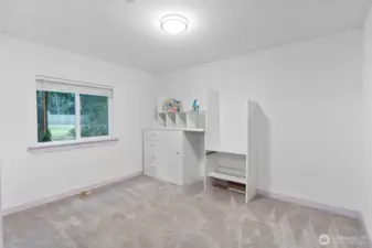 A spacious third bedroom with plush carpeting, a large window overlooking the yard, and plenty of room to configure a desk, bed, or storage. Simple lines and neutral walls make it easy to tailor the space to any use, from a hobby room to a comfortable bedroom.