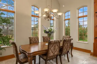 Lightfilled dining room is surrounded by immense windows overlooking the back gardens.
