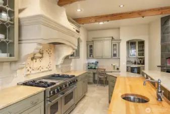 Viking Double Range with commercial vent-a-hood housed in a beautiful Limestone chimney. Marble and butcher block counters team up with the stainless prep sink. Pot filler over the stove.