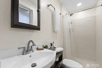 The updated primary bath makes good use of the space with added storage and a shower. Obscure glass adds privacy.