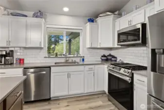 Stainless appliances, white cabinetry and quartz countertops w/subway tile give this kitchen a modern farmhouse vibe.