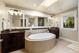 View of tile and granite 5 piece master bath with garden jetted soaking tub, large horizontal mirrors, skylights and oil rubbed bronze lighting.