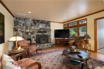 Main floor living room with wood insert fireplace, rock surround and wood flooring.