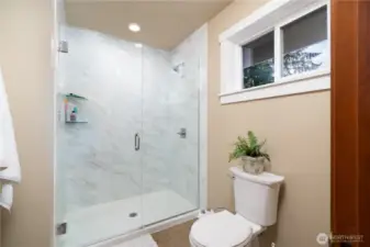 Primary 3/4 bathroom with large walk-in tile shower and glass door.