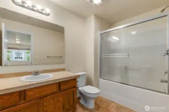 The private Primary Bathroom features a tub/shower combo with full glass enclosure. The large vanity offers great storage, tile counters and an expansive mirror.