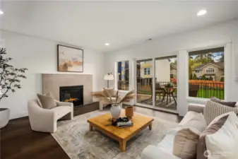 Great Room with Balcony Access: Sliding glass doors open to a covered outdoor patio, extending living space into the fresh Northwest air. Perfect for morning coffee or evening relaxation, this space enhances indoor-outdoor connection with a fully fenced backyard beyond.    Photos are from THIS model home at Foxmoore but are for visualization purposes only.  Photos are from the model home at Foxmoore and for visualization purposes only. Plans, colors, building orientation, finishes, home outlook, and other details can and WILL vary.