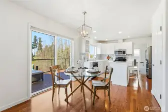 Bright dining area with hardwood floors and sliding glass doors to the deck, filling the space with natural light and peaceful views.