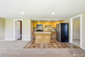 ADU kitchen with quartz counters, island seating, and abundant cabinetry, opening to a spacious living area.
