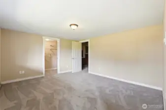 ADU primary bedroom with an oversized walk-in closet featuring a built-in organization system and door to more storage space.