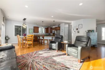 A view from the great room, looking back to the kitchen and dining area.  Entry at far right.  Hall in the middle leads to utility room (behind kitchen) and a 3/4 guest bath (behind the wall with the Ks and 5s on it).  Warm oak flooring makes the main floor feel homey and cozy.
