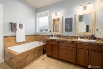 Main floor primary en-suite features tile floor with decorative tile inlay to match the double vanity.  Separate soaking tub and shower.  Walk-in closet.