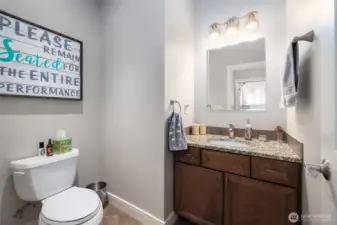 Main floor guest 3/4 bathroom has a shower, granite topped vanity, tile floor.